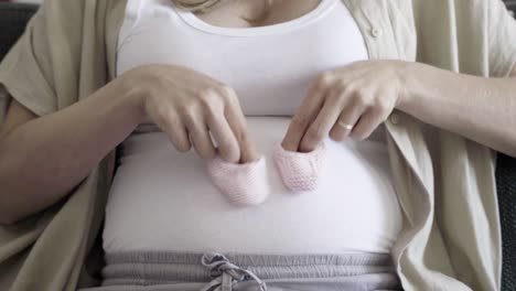Schwangere-Frau-Spielt-Mit-Babyschuhen-Auf-Dem-Bauch